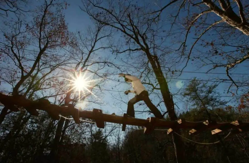 richland creek zipline asheboro north carolina. woman walking across a narrow wooden bridge