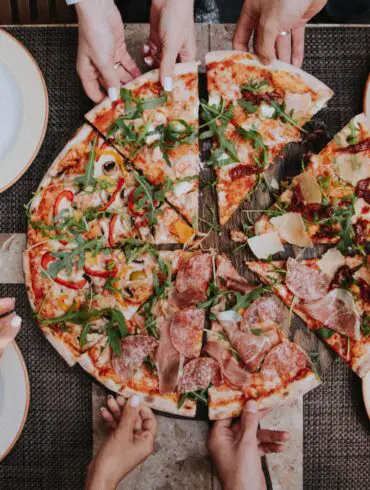 people grabbing a pizza