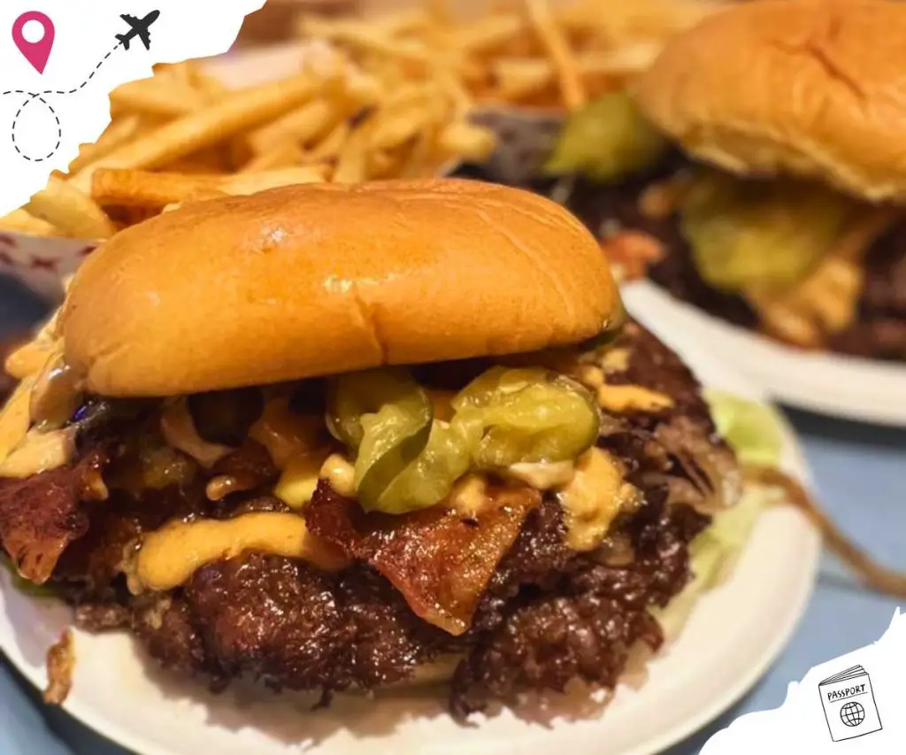 Close up of a Double Smashburger with bacon with another burger and fries in the background