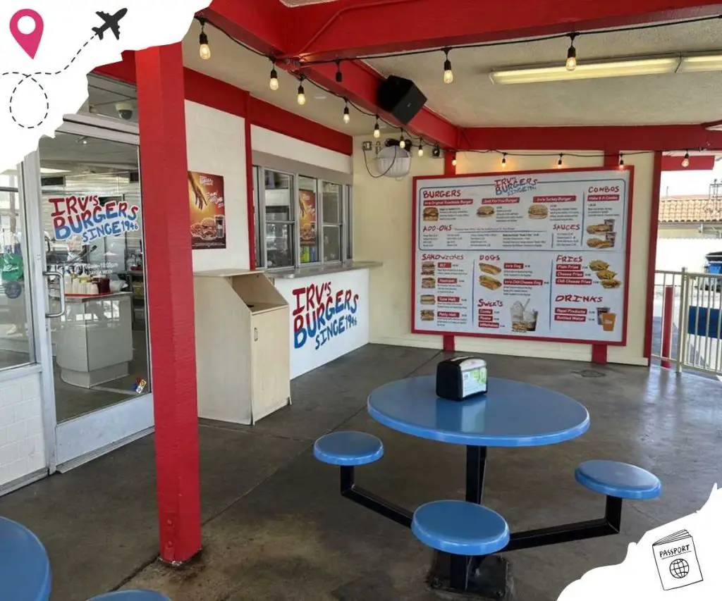 Outdoor patio with a large menu in front of the ordering booth. There are round blue tables with round blue stools in the area.