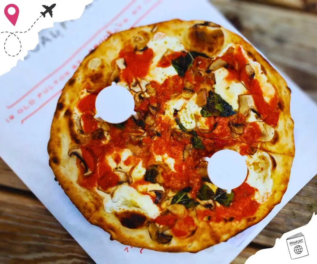 A small Margherita pizza on a napkin placed on a wooden table.