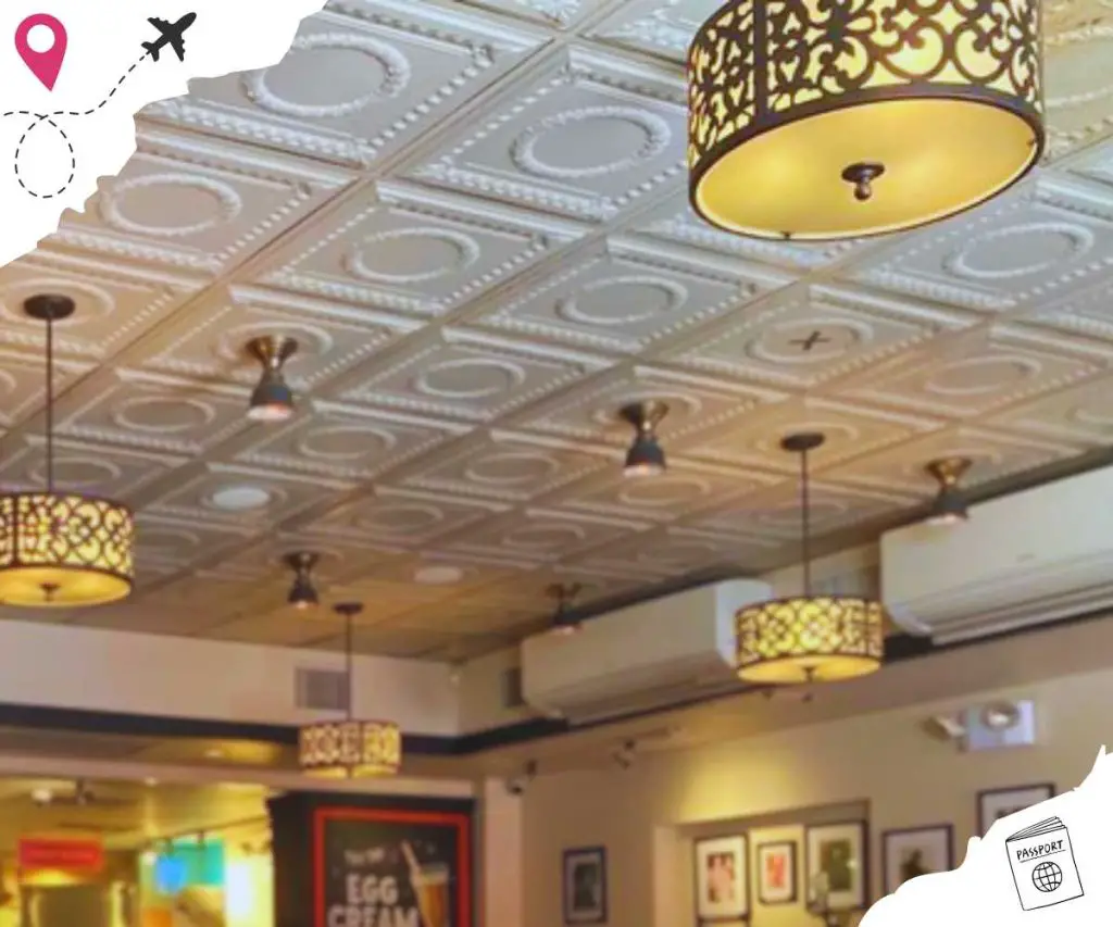 The ceiling of the restaurant, which is adorned with intricate white tiles and elegant yellow flat cylindrical lights.