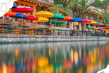 Colorful outdoor cafe with vibrant umbrellas along a waterway, perfect for scenic dining and exploring local destinations.