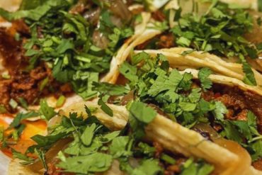 Authentic Mexican street taco with seasoned beef, fresh cilantro, chopped onions, crispy lettuce, and lime wedge on a white plate. Typical Mexican cuisine for food lovers and travelers exploring Mexico.