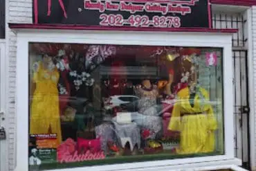 Bright clothing boutique storefront with stylish dresses and accessories, colorful window display, pink and yellow garments, perfect for fashion shopping, located in a trendy shopping district.