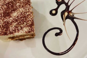 Rich chocolate dessert with a decorative chocolate swirl on a white plate, suitable for travel and food lovers. Perfect for sharing at cafes or restaurants during your travel adventures.