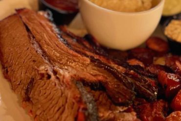 Juicy smoked barbecue ribs served with mashed potatoes, baked beans, and barbecue sauce, perfect for a delicious American barbecue meal.