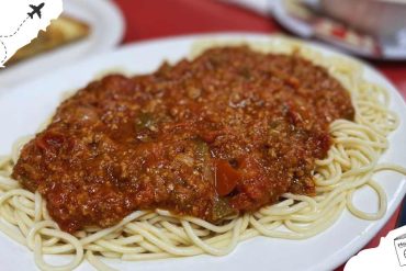 Spaghetti Bolognese on a white plate featuring rich meat sauce and cooked pasta, perfect for authentic Italian cuisine and travel foodie experiences.