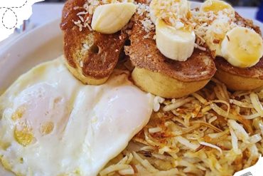 Banana French Toast with fried eggs and crispy hash browns, served for breakfast or brunch in a cozy restaurant setting, perfect for exploring culinary destinations worldwide.