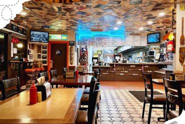 Colorful restaurant interior with decorative ceiling featuring photos and tropical fish on the walls, offering a cozy dining atmosphere with a vibrant travel and ocean theme for tourists and locals.