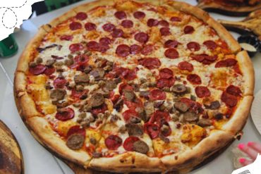 Pepperoni and sausage pizza on a wooden serving board, served at a casual restaurant, showcasing classic American pizza flavors, perfect for travel food experiences and culinary adventures.