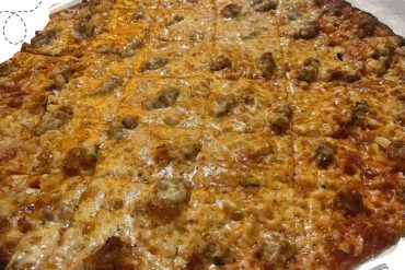 Savory cheese and sausage pizza with melted cheese on a crispy crust, served on a metallic tray, perfect for a delicious meal or snack.