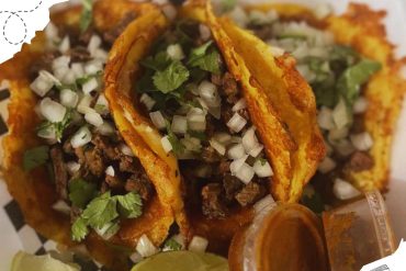 Beef tacos with chopped onions and cilantro, served with lime wedges and hot sauce, showcasing Mexican cuisine in a vibrant and flavorful dish.