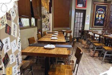 Japanese restaurant interior with wooden tables and chairs, traditional decor, Japanese banners, and wall art, creating an authentic dining atmosphere. Perfect for travelers seeking Japanese cuisine.