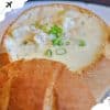 Creamy crab and scallop chowder served in a bread bowl with green onions on top, ideal for travel food experiences.