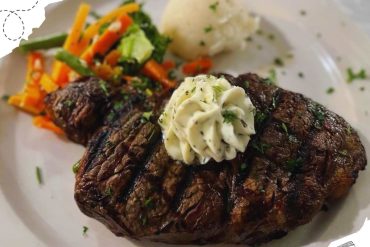 Succulent grilled steak with herb butter, served with mashed potatoes and colorful sautéed vegetables on a white plate, gourmet restaurant meal, fine dining food presentation, culinary art.
