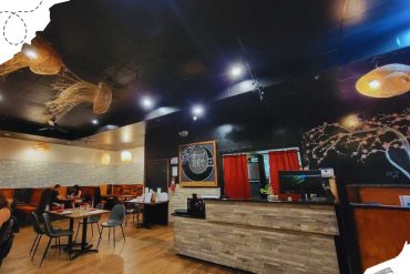 Modern Asian restaurant interior with decorative hanging lanterns and artistic wall murals, featuring a cozy atmosphere perfect for dining and travel experiences.