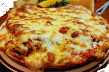 Cheesy baked lasagna with melted cheese, ground meat, and tomato sauce served on a plate. Perfect comfort food for Italian cuisine lovers.