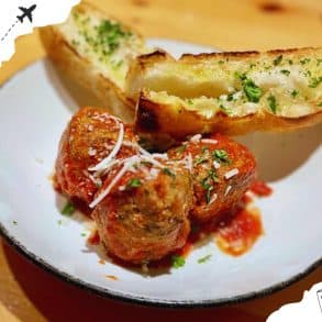 Delicious Italian meatballs with tomato sauce and cheesy garlic bread, perfect for travel food experiences. Enjoy authentic flavors from Italy while exploring culinary destinations worldwide.