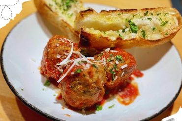 Delicious Italian meatballs with tomato sauce and cheesy garlic bread, perfect for travel food experiences. Enjoy authentic flavors from Italy while exploring culinary destinations worldwide.