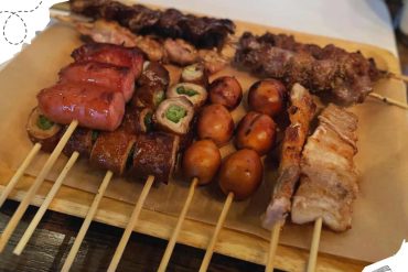 Marinated skewers with beef, chicken, and vegetables served on a wooden platter, perfect for tasting authentic street food flavors. Popular Asian barbecue dishes showcased on a rustic tray.