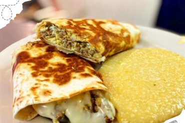 Savory breakfast burrito with melted cheese and meat, served with a side of creamy polenta, close-up, delicious Mexican-inspired comfort food, perfect for travel culinary adventures.