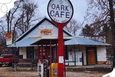 Vintage Oak Cafe in Oak Arkansas, established in 1890, with classic roadside signs, surrounded by leafless trees, offering a nostalgic travel destination for visitors exploring historic South Arkansas.