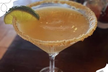 - Refreshing margarita cocktail with salted rim and lime wedge on a wooden table.