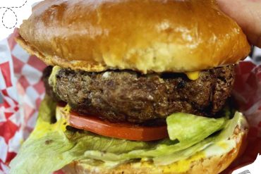 Juicy cheeseburger with fresh lettuce, tomato, and crispy bun, showcasing delicious American fast food. Perfect for food lovers exploring top travel destinations with renowned cuisine.