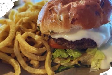 Comfort food burger with fries served at a travel-themed restaurant, capturing a delicious meal for travelers seeking local culinary destinations.