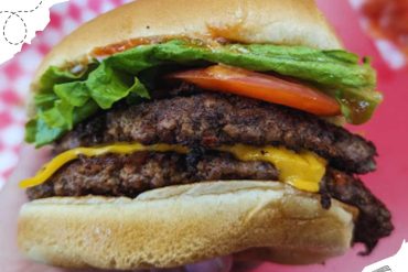 Beef burger with melted cheese, fresh lettuce, tomato, and pickles on a toasted bun, ideal for travel food in popular destinations, close-up shot.