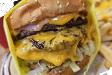 Juicy cheeseburger with melted cheddar, beef patty, lettuce, and toasted bun served in a fast-food setting. Perfect for travel-friendly meals and road trips around popular destinations.