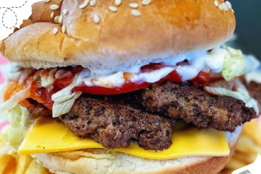 Savory burger with crispy beef patty, cheddar cheese, fresh lettuce, tomato, and creamy mayonnaise on a sesame seed bun, highlighting delicious American fast food.