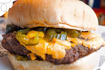 Succulent cheeseburger with pickles and melted cheese on a toasted bun, close-up shot, delicious American fast food, gourmet burger, comfort food, casual dining, tasty burger with fresh ingredients, food photography.