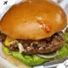 Juicy beef burger with melted cheese, fresh lettuce, and red onions on a toasted bun, perfect for exploring local foods on your travel adventures.