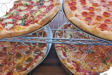 Delicious assorted pizzas on metal racks, featuring pepperoni, sausage, and veggie toppings, served at a restaurant for a delightful dining experience.