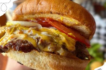Cheeseburger with melted cheese, fresh tomato, onions, and a toasted bun, showcasing a delicious American fast food meal for travel and food lovers.