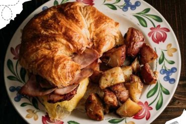 Roast chicken with crispy skin served with roasted potatoes on a floral patterned plate.