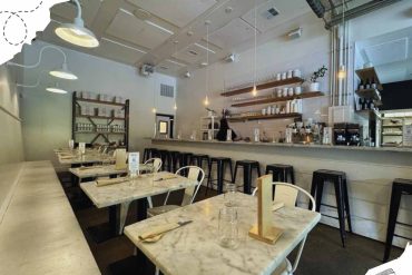 Modern cozy cafe interior with marble tables, white chairs, open kitchen and minimalist decor, perfect for destination travel, food lovers, and relaxing dining experiences.