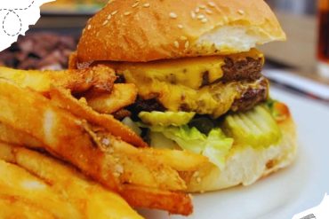 Cheeseburger with fries on a white plate, crispy golden fries in the foreground, juicy beef patty with melted cheese, lettuce, and a sesame seed bun, delicious American fast food meal, blurred restaurant background.