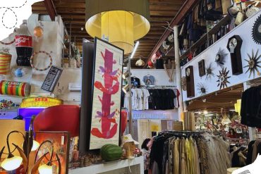 Colorful thrift store with clothing, decorative items, and artwork; vibrant shopping atmosphere for unique souvenirs and vintage fashion.