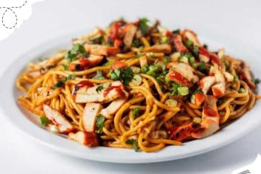 Savory Asian noodle stir-fry with grilled chicken, fresh vegetables, and a drizzle of sauce on a white plate, perfect for travel-inspired cuisine.