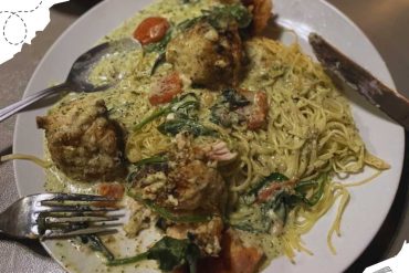 Creamy chicken and vegetable pasta dish with herbs, served with fried chicken pieces on a white plate, featuring a rich sauce and fresh ingredients, perfect for travel food experiences.