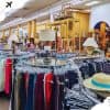 Second: Wide-angle view of a thrift store filled with clothing, accessories, lamps, and decor items, showcasing vintage finds and secondhand shopping experiences.