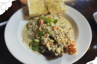 Fluffy shrimp and vegetable casserole topped with green onions served with bread on a white plate.