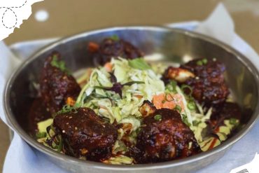 Succulent grilled chicken wings with fresh vegetable coleslaw in stainless steel serving dish for travel or outdoor picnic meal.