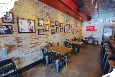 Vintage restaurant interior with exposed brick walls, black and white photos, wooden tables, and a retro vibe. Perfect for travel and dining enthusiasts seeking unique destinations.