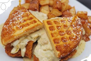 Crispy fried chicken and waffle sandwich with melted cheese and potato wedges on side, comfort food dish, American cuisine, breakfast or brunch meal, appealing presentation, hearty and delicious comfort food.