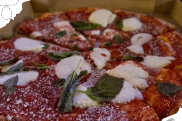 Fresh Margherita pizza with tomato sauce, mozzarella cheese, basil, and grated Parmesan in a cardboard box. Perfect Italian cuisine for travel food lovers.