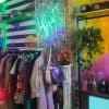 Vibrant thrift store interior with colorful neon sign, clothing rack, and vintage decor highlighting eclectic fashion shopping experience.